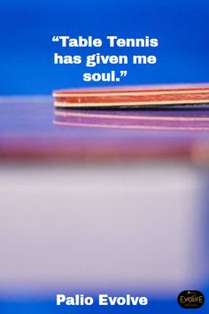 the table tennis racket has been placed on top of the blue tablecloth, with an inspirational quote above it