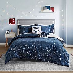 a bed with blue and white comforter in a bedroom next to a night sky wall