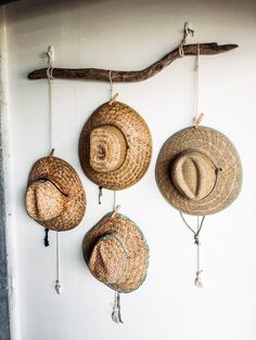 three straw hats hanging from hooks on a wall