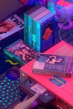 a person is pointing at some books on a table with neon lights in the background