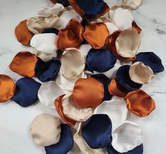 several different colored flowers on a white marble counter top with blue and orange satin petals