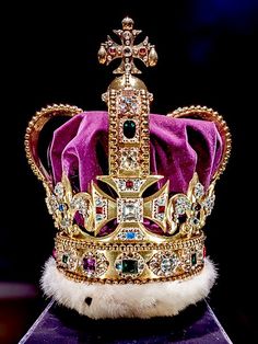 a purple crown with gold trim and jewels on it's head is sitting on top of a blue box