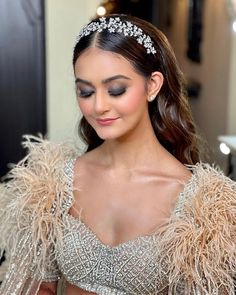 a woman wearing a tiara with feathers on her head and dress in the background