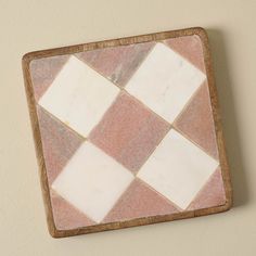 a pink and white checkered tile on a wall with a wooden frame in the middle