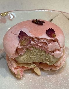 a half eaten doughnut sitting on top of a white plate covered in pink and green frosting