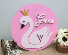 a pink plaque with a white swan and the words grace on it next to flowers