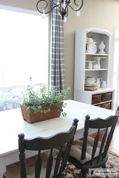 a dining room table with two chairs and a potted plant on top of it