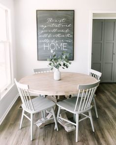 a dining room table with four chairs and a chalkboard on the wall above it