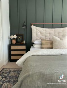 a bed that has some pillows on top of it in a room with green walls