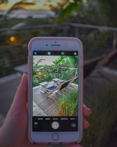 someone is holding up their cell phone to take a picture of the pool and deck