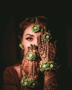 a woman holding her hands up to her face with henna designs on it's palms