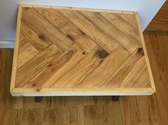 a wooden table sitting on top of a hard wood floor next to a white wall