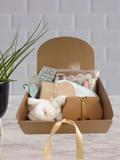 an open box filled with items sitting on top of a table next to a potted plant