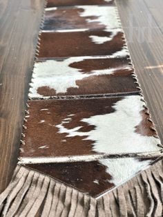 a cowhide rug with fringes on it sitting on top of a wooden floor