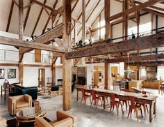 a large open room with lots of furniture and tables in the center is full of wood beams