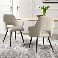 two chairs sitting on top of a rug in front of a table with a potted plant