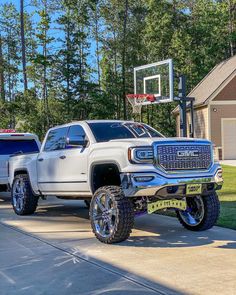 a white truck parked on top of a driveway next to a basketball hoop in front of a house