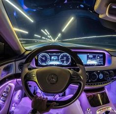 the interior of a car with purple lighting and dashboard lights, including steering wheel and gauges