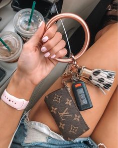 a woman is sitting in her car holding a keychain and cell phone holder