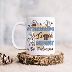 a coffee mug sitting on top of a piece of wood next to a pine cone