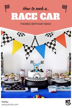 a table topped with cakes and desserts next to a wall decorated with race flags