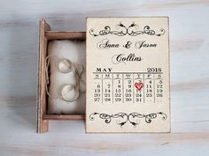 a wedding date card in a wooden box with two white balls inside and the date on it