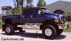 a blue monster truck parked in front of a building