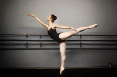 a ballerina in black leotard standing on one leg