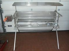 a stainless steel grill sitting on top of a red tile floor next to a white garage door