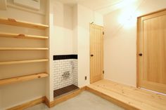 an empty room with wooden shelves and white tile on the wall, along with open closet doors