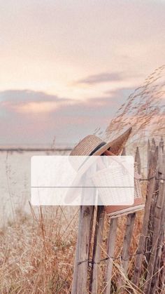 a person sitting on a wooden bench next to a fence and looking at the water