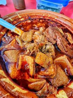 a bowl filled with meat and sauce on top of a table