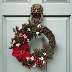 a wreath with poinsettis and greenery hangs on the front door handle