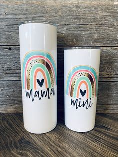 two white coffee mugs with the words mama and rainbow painted on them sitting next to each other