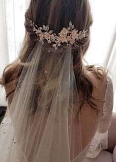 the back of a bride's head wearing a wedding veil with flowers on it