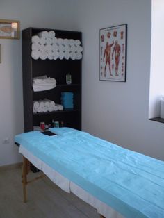 a blue bed in a room with towels on the shelves above it and pictures on the wall