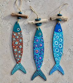 three colorful fish hanging from hooks on a wall