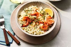 a bowl filled with rice and shrimp on top of a table next to a fork