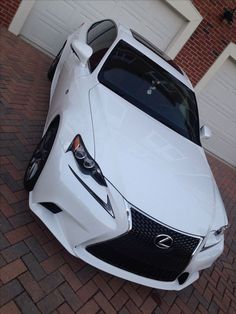 a white sports car parked in front of a garage with its hood up and lights on