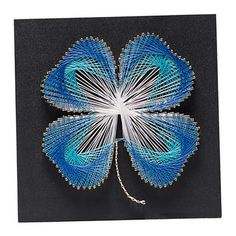 a blue and white butterfly made out of wire on a black surface with gold accents