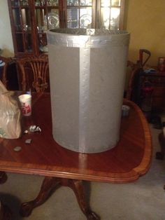 a large metal trash can sitting on top of a wooden table