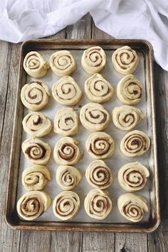 a pan filled with cinnamon rolls on top of a wooden table