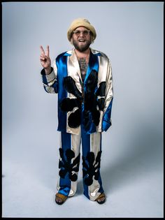 a man in a blue and white suit making the peace sign