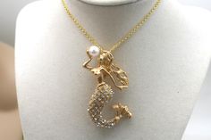 a gold necklace with a little mermaid on it