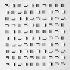 several square pieces of paper are arranged on a white surface