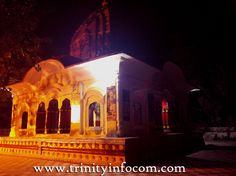 a lit up gazebo sitting in the middle of a park next to a building