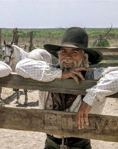 an old man leaning on a wooden fence