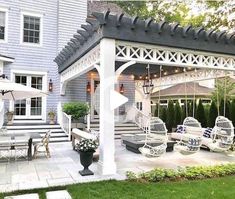 an outdoor living area with white furniture and umbrellas on the patio, next to a blue house