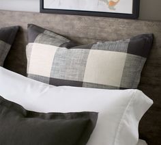 a bed with black and white pillows on it's headboard next to a framed photograph