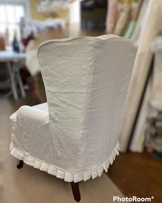 a white chair with ruffles on it sitting in a room filled with furniture